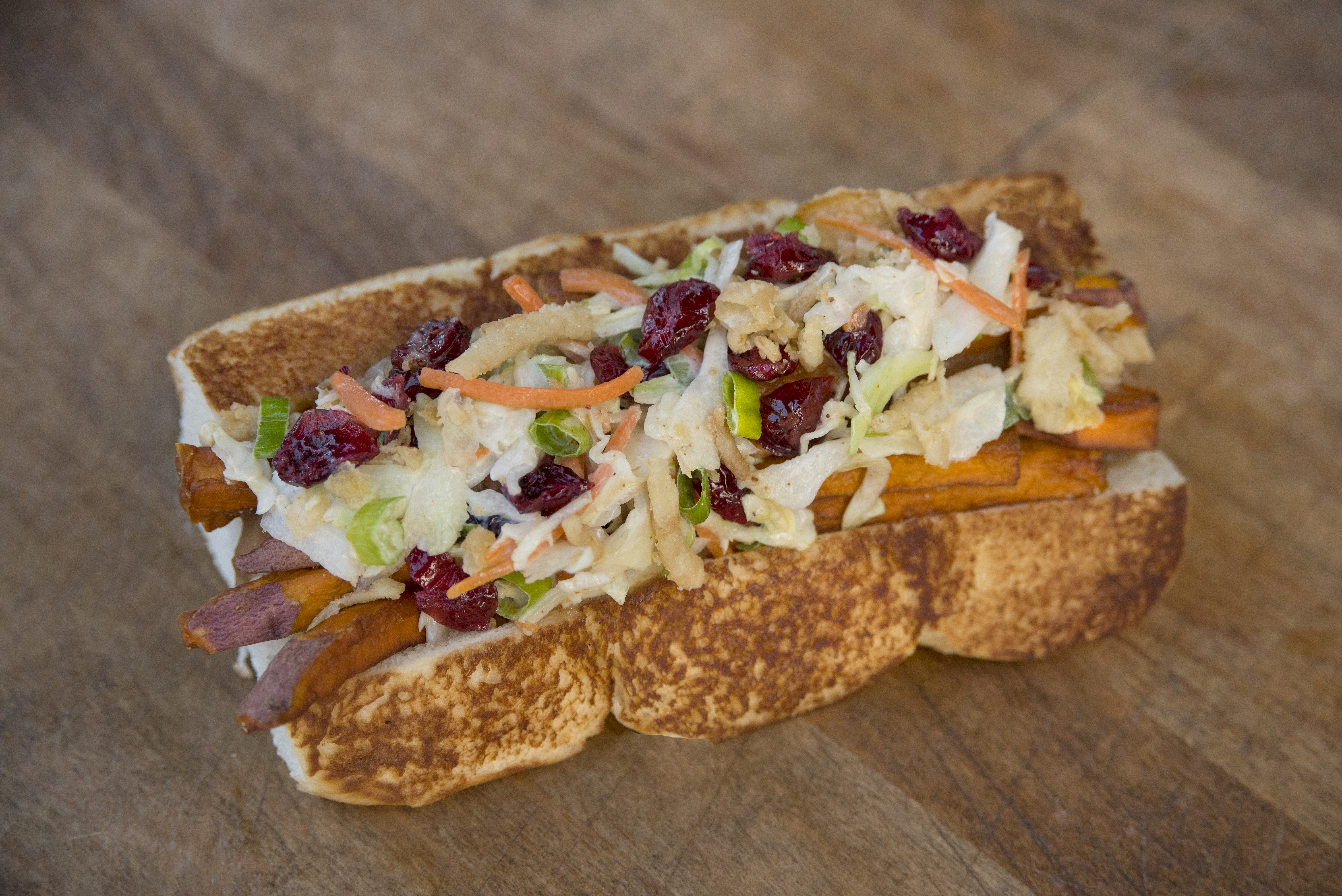 Final Build: turducken sausage topped with sweet potato fries, sage gravy, cranberry slaw and crispy onions, all served on grilled Hawaiian rolls.